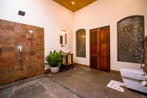 马拉利库兰Flamingo Boutique Hotel & Ayurvedic spa的带淋浴、卫生间和盥洗盆的浴室