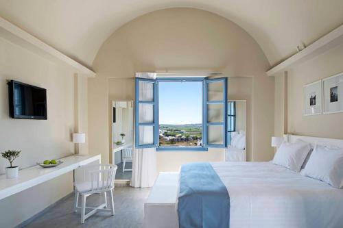 阿克罗蒂里Acroterra Rosa Luxury Suites & Spa的卧室设有一张白色大床和一扇窗户。
