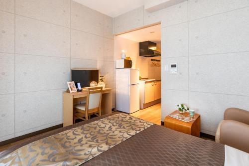 名户Condominium Hotel Likka in Nago的一间卧室配有一张床、一张书桌和一台冰箱
