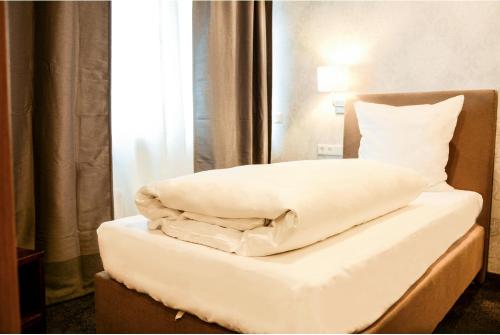 伍珀塔尔蓝德霍夫酒店的一张带白色床单和枕头的床