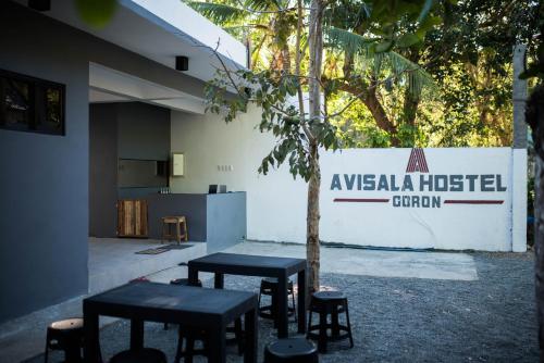 科隆Avisala Hostel Coron的一组桌子和凳子在建筑物前