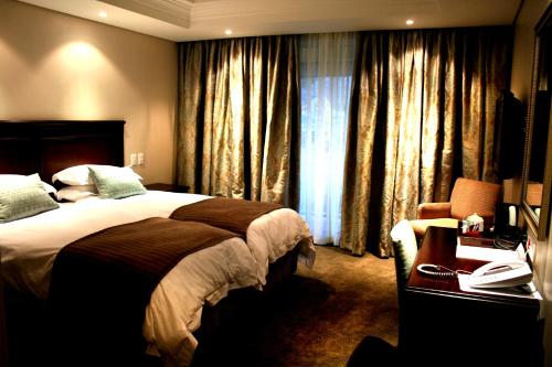 昆斯敦Queens Casino and Hotel的配有一张床、一张书桌和一扇窗户的酒店客房