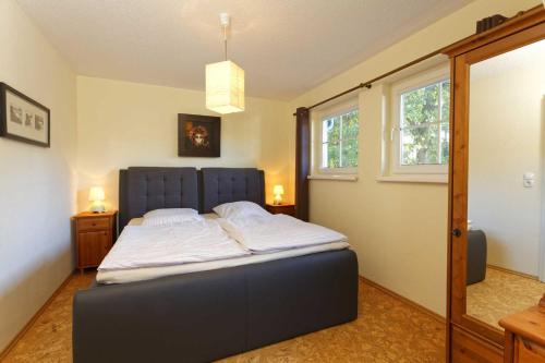 奥斯特西巴德钦诺维茨Zinnowitz Skanepark Ferienhaus 28的一间卧室配有一张带蓝色床头板的床和两个窗户
