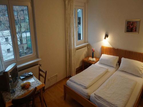 弗莱堡Hotel-Pension Goldene Krone的一间卧室配有两张床和一张书桌及电视