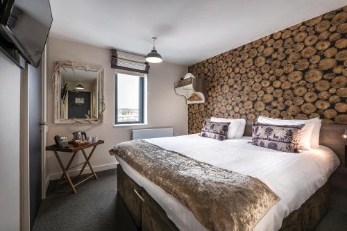 纽伯里洛奇酒店的一间卧室设有一张大床和一堵木墙