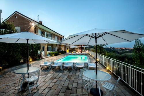 马切拉塔Holiday Residence Belohorizonte的游泳池旁带桌子和遮阳伞的天井