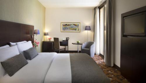 巴格达Babylon Rotana Hotel的酒店客房设有一张大床和一张书桌。