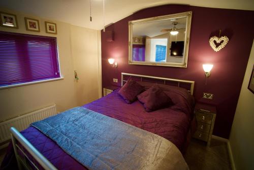 West ChiltingtonLuxurious Rural Cabin with Hot Tub的一间卧室配有一张带紫色床单和镜子的床