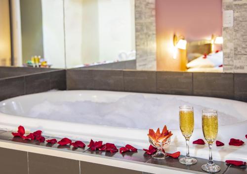 基多Hostal Oro Orense的浴缸配有两杯香槟和玫瑰