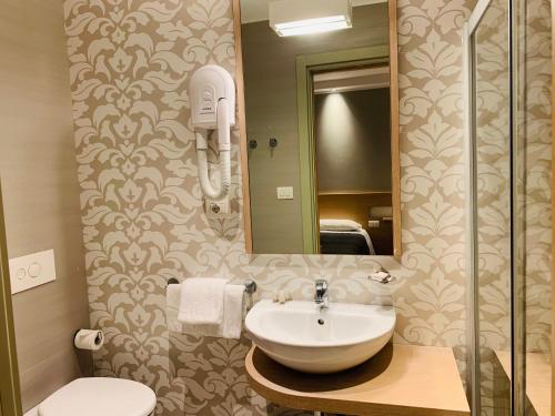 里乔内Hotel Liane Riccione的一间带水槽、镜子和卫生间的浴室