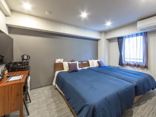 札幌HOTEL LiVEMAX Sapporo Susukino的一间卧室配有蓝色的床和一张书桌