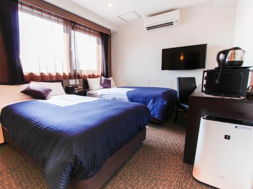 大阪HOTEL LiVEMAX Osaka Dome Mae Hotel的酒店客房设有两张床和一台平面电视。