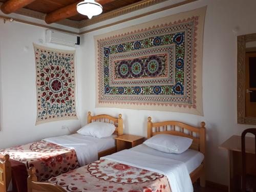 布哈拉布哈拉萨曼尼住宿加早餐旅馆的墙上挂挂挂毯的房间里设有两张床
