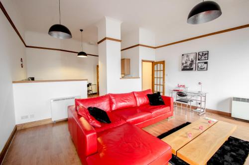 阿伯丁City Centre Orange Apartments Bastille的客厅里一张红色的沙发,配有桌子
