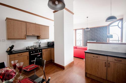 阿伯丁City Centre Orange Apartments Bastille的厨房配有木制橱柜和红色沙发