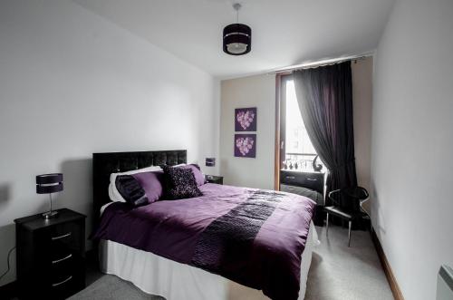 阿伯丁City Centre Orange Apartments Bastille的一间卧室设有紫色的床和窗户