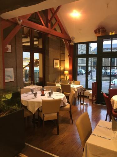 圣马洛Hotel Brasserie Armoricaine的餐厅设有白色的桌椅和窗户。