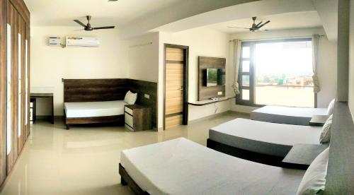钱德加尔Pride Home的一间卧室配有三张床和电视。
