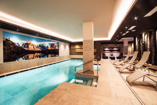 摩德纳迪-坎皮格里奥西姆多罗酒店的一座酒店游泳池周围设有椅子
