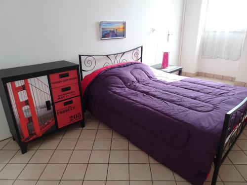 圣纳泽尔Hébergement Paquebot de Rêve的一间卧室配有紫色的床和梳妆台