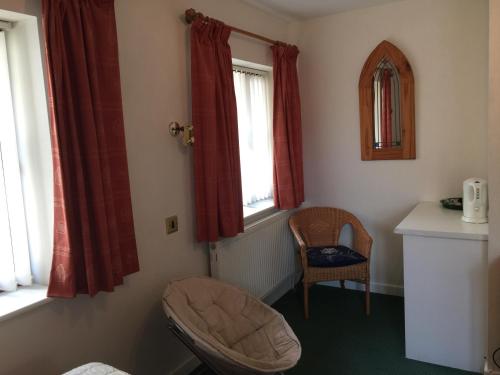 切普斯托Parkfield (Chepstow BnB)的一个带椅子和两个窗户的房间的角落