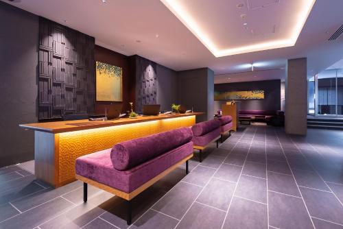 京都京都维斯塔普瑞米欧那果米泰酒店的大堂设有酒吧,配有一排紫色椅子