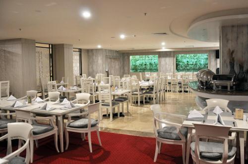 名古屋Beverly Hotel Batam的一间设有白色桌椅的用餐室