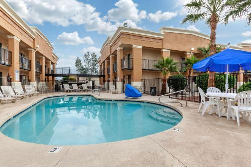 梅萨Quality Inn & Suites near Downtown Mesa的一座带桌椅的大楼前的游泳池