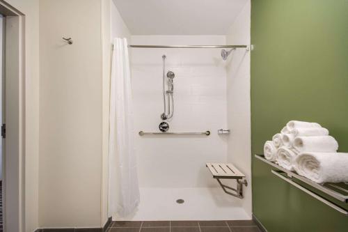 育空Sleep Inn & Suites Yukon Oklahoma City的浴室设有绿色墙壁和毛巾,配有淋浴。
