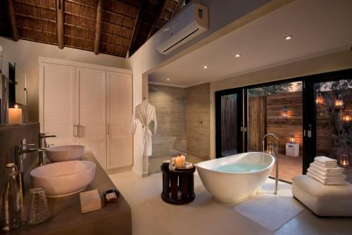 萨比沙禁猎区Lion Sands River Lodge的浴室配有两个盥洗盆和浴缸。