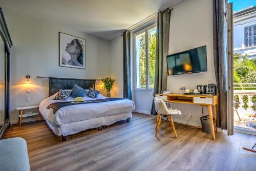 戛纳Villa Claudia Hotel Cannes Centre - Parking的一间卧室配有一张床和一张带电脑的书桌