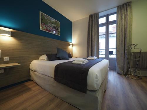 维希Hôtel Le Biarritz - Vichy的一间设有大床和窗户的酒店客房