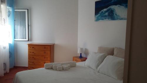 卢斯Cantinho Das Estrelas, Luz Lagos的一间卧室配有一张带白色床单的床和梳妆台。