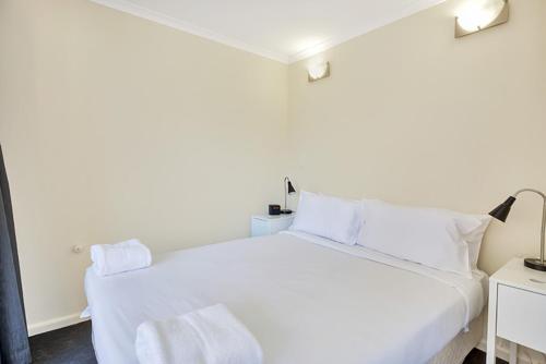 悉尼City apartment at College St的卧室内的白色床和白色枕头