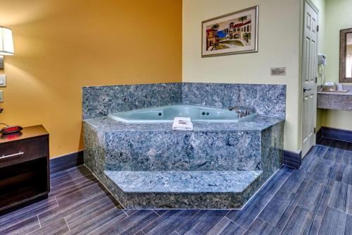 布朗斯维尔Quality Inn - Brownsville的浴室设有大浴缸,铺有木地板
