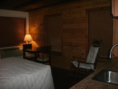 密歇根城冷泉旅馆的一间卧室配有一张床、一张桌子和一个水槽