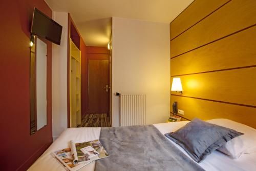 巴黎贝朗布阿城市酒店的一间卧室配有一张带木制床头板的床