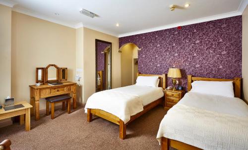 波克灵顿The Feathers的一间卧室设有两张床和紫色墙壁