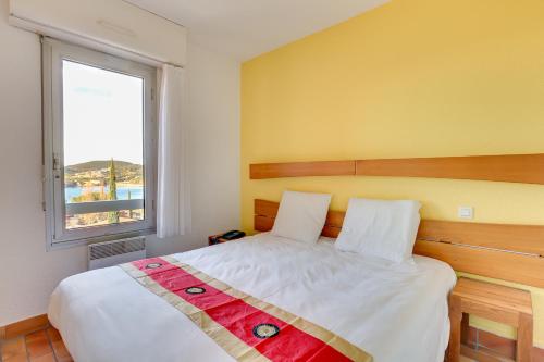 阿盖Village Club Les Mas de L'Esterel的一间卧室设有一张大床和窗户