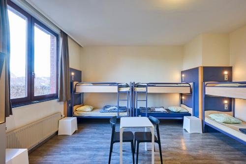 布鲁塞尔欧洲世代青年旅舍的客房设有三张双层床和一张桌子及椅子。