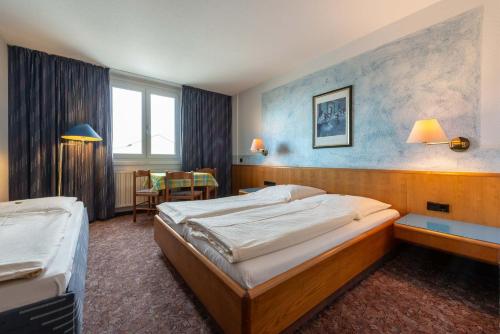 斯图加特enjoyHotel garni Korntal Stuttgart的酒店客房设有两张床和一张桌子。