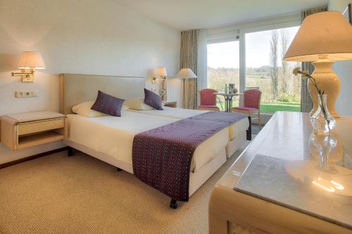 斯莱纳肯Hotel & Appartement de Zevende Heerlijkheid的一间卧室配有一张床、一张桌子和一个窗户。