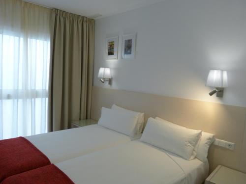 加的斯Apartamentos Patagonia Sur的一间卧室配有一张带白色床单的床和一扇窗户。