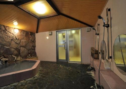 野沢Address Nozawa Japanese Room / Vacation STAY 22751的带浴缸和石墙的大浴室