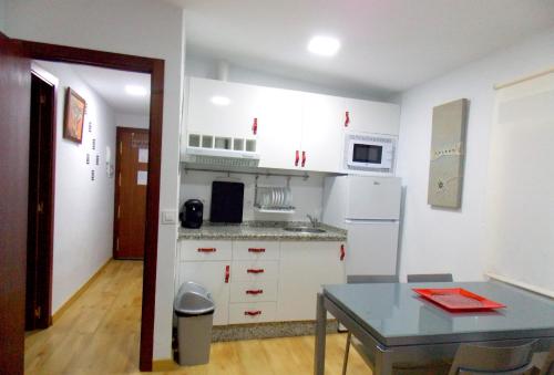 普拉森西亚Apartamentos Capuchinas的厨房配有白色橱柜和桌子