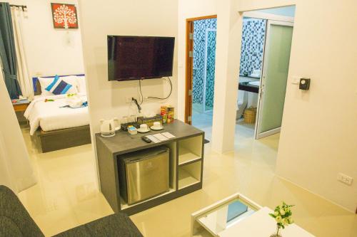 湄南海滩Adarin Beach Resort的带电视的客厅和配有床的房间