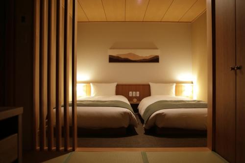 白川村Onyado Yuinosho的酒店客房设有两张床和窗户。
