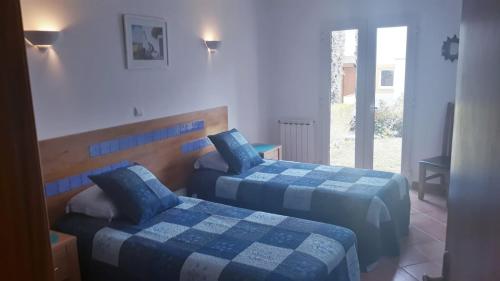 塔维拉Garden Apartment Quinta do Morgado的一间卧室设有两张带蓝色床单的床和窗户。