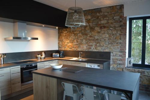 费瑞雷斯Gite Terre de ciel的厨房设有黑色柜台和石墙