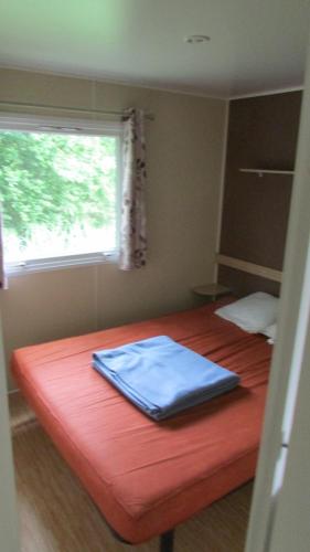 圣乔治-德迪多讷Mobil Home 3 ch的一间卧室配有一张红色的床和窗户